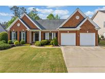 Charming brick home with a well-manicured lawn and landscaping at 1435 Harburn Ct, Cumming, GA 30041