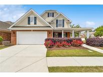 Charming two-story home featuring a brick and tan exterior with a two-car garage and manicured front yard at 2055 Hickory Station Cir, Snellville, GA 30078