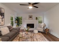 Bright living room features a brick fireplace, ceiling fan, hardwood floors and lots of natural light at 607 Hickory Creek Ln, Woodstock, GA 30188