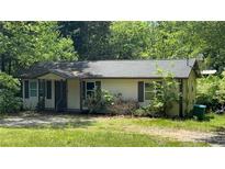 Quaint one-story home with siding and a cozy front porch nestled among mature trees at 2888 Mountain View Rd, Snellville, GA 30078