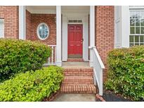 Inviting front entry featuring a red door, brick facade, and lush landscaping at 3270 Golfe Links Dr, Snellville, GA 30039