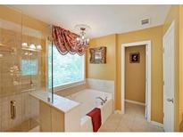 A relaxing bathroom showcasing a soaking tub beneath a window, plus glass shower, and decorative lighting at 718 Province Se Pl, Atlanta, GA 30312