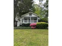 Charming home featuring a cozy front porch, surrounded by lush greenery and vibrant flowers, creating a welcoming curb appeal at 1311 Sylvan Cir, Brookhaven, GA 30319