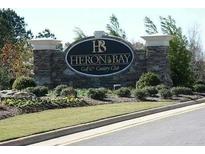 Stone sign for Heron Bay Golf & Country Club with manicured landscaping in a suburban setting at 1213 Dawnview Dr, Locust Grove, GA 30248