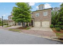 Charming brick townhome with attached two-car garage, mature tree, and well-manicured lawn at 125 Windy Pines Pass, Roswell, GA 30075