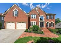 Two-story brick home with a manicured lawn, two-car garage, and brick stairs leading to the front door at 2436 Camden Lake Nw Vw, Acworth, GA 30101