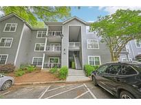 View of exterior of a two-story condo building with gray siding, balconies, landscaping, and parking at 7104 Santa Fe Pkwy, Atlanta, GA 30350