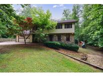 Charming two-story home with stone accents, attached garage, and lush greenery at 10565 Shallowford Rd, Roswell, GA 30075