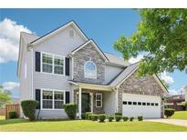 Charming two-story home boasts stone accents, manicured lawn, and attached two car garage at 5512 Village Rdg, Fairburn, GA 30213