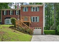 Charming brick home featuring a wooden deck, lush green lawn, and convenient garage access at 187 Timber Creek Sw Ln, Marietta, GA 30060