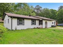 Charming single-story home with a classic white brick exterior and lush green lawn at 2744 Preston Dr, Decatur, GA 30034