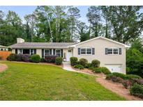 Ranch-style house with charming curb appeal, mature trees, and a well-maintained lawn at 299 Stockwood Dr, Woodstock, GA 30188