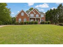 Charming two-story red brick home with manicured lawn and symmetrical design, showcasing classic curb appeal at 2111 Fernbank Way, Dacula, GA 30019