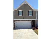 Two-story townhome with a large two car garage, neutral siding and black shutters at 11692 Mendenhall Ct, Hampton, GA 30228