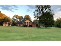Beautiful brick home with a spacious lawn and mature trees, showcasing classic architecture and curb appeal at 130 Plantation Dr, Stockbridge, GA 30281