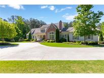 Stately home featuring a manicured front lawn, circular driveway and mature landscaping under a beautiful sky at 101 Morgan Ln, Canton, GA 30115
