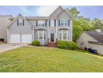 Charming two-story home featuring a two-car garage and a well-maintained front lawn with bushes at 229 Millwheel Dr, Villa Rica, GA 30180