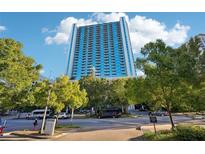 Modern high-rise building boasts floor-to-ceiling windows, reflecting the sky, and beautiful landscaping around the community at 3324 Peachtree Ne Rd # 1104, Atlanta, GA 30326