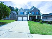 Inviting two-story brick home with a manicured lawn, covered porch, and a two-car garage at 545 Eldridge Dr, Suwanee, GA 30024
