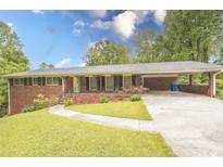 Charming brick home with well-manicured front yard and a covered carport at 3560 Emily Way, Atlanta, GA 30349