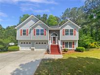 Charming home with a two-car garage, red shutters, and a stone accent, surrounded by mature trees and lush greenery at 156 Hawthorn Dr, Carrollton, GA 30116