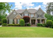 Charming two-story home featuring a well-manicured lawn, stone accents, and a welcoming front porch with rocking chairs at 3309 Nw Past Nw Pl, Kennesaw, GA 30152