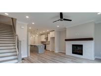 Bright living room with fireplace, modern ceiling fan, and stairs to the upper level at 1976 Deco Dr, Kennesaw, GA 30144