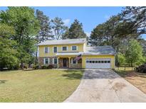 Inviting two-story home with yellow siding, stone accents, front porch and attached garage at 2100 Ann Se Ct, Conyers, GA 30013