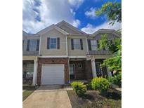 Two-story townhome featuring a brick and neutral-toned facade, attached garage, and well-maintained landscaping at 1529 Iris Walk, Jonesboro, GA 30238
