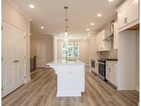 Bright kitchen features a large island, white cabinets, stainless steel appliances, and modern pendant lighting at 1995 Deco Dr, Kennesaw, GA 30144