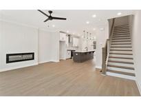 Open concept living space features a fireplace, a kitchen with a large island, and stairs leading to the upper level at 1995 Deco Dr, Kennesaw, GA 30144