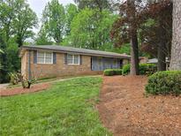 Traditional brick ranch home featuring mature trees, green lawn, and dark shutters at 1810 Trophy Dr, Marietta, GA 30062