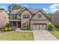 Beautiful two-story home with a brick and stone facade, manicured lawn, and two-car garage at 2435 Sentinel Chase Way, Cumming, GA 30041