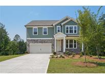 Charming two-story home featuring a stone and green-paneled facade, a two-car garage, and a well-manicured front lawn at 7252 Eton Ln, Locust Grove, GA 30248