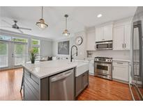 Modern kitchen featuring a large island with marble countertop, stainless steel appliances, and hardwood floors at 62 High Top Pt, Sandy Springs, GA 30328