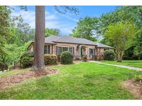 Charming brick home featuring a lush green lawn, mature trees, and colorful landscaping at 2790 Westhampton Way, Tucker, GA 30084