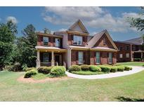 Charming two-story brick home with a welcoming front porch and manicured landscaping at 2405 Brisbane Dr, Conyers, GA 30013
