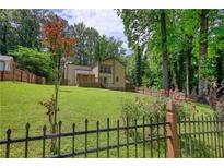 Spacious backyard featuring lush green lawn, privacy fence, and a charming two-story house at 2926 Swarthmore Dr, Lawrenceville, GA 30044