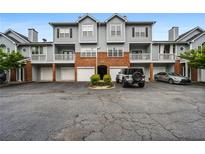 Exterior of a townhome with gray siding, brick accents, attached garages, and parking spaces at 508 Vinings Forest Se Ct, Smyrna, GA 30080