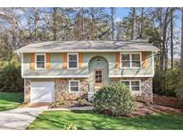 Charming split-level home with stone accents, attached garage, and well-maintained front yard at 875 Waterbrook Ct, Roswell, GA 30076