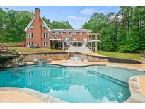 Beautiful backyard pool area with waterfall feature, gazebo, and brick house backdrop at 1212 Lee Whatley Dr, Lithonia, GA 30058