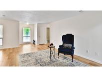 Bright living room featuring hardwood floors, a modern rug, and a comfortable blue accent chair at 8740 Roswell Rd # 9C, Atlanta, GA 30350