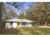 Charming single-story home features a yellow door and attached carport, nestled among mature trees at 2013 Ridge Rd, Dallas, GA 30157