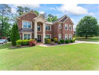 Beautiful brick home with a well-manicured lawn and colorful landscaping, creating a welcoming curb appeal at 305 Spooner Dr, Mcdonough, GA 30252