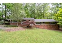 Charming single-story brick home with a well-manicured lawn and mature trees providing shade at 4052 Shawnee Ne Ln, Brookhaven, GA 30319