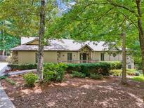 Charming home with stone accents, wood siding, and lush landscaping in a serene, wooded setting at 211 Black Kettle Ln, Johns Creek, GA 30022