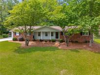 Charming single-story home with a brick facade, a lush green lawn, and mature trees providing shade at 4444 Bending River Sw Trl, Lilburn, GA 30047