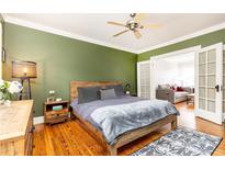 Relaxing bedroom features hardwood floors, green accent wall, wooden bed frame, and access to a living space at 1125 Briarcliff Ne Pl # 14, Atlanta, GA 30306