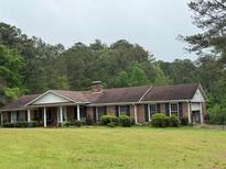 Charming single-story brick home with a cozy front porch and a lush green lawn surrounded by trees at 1935 Flat Shoals Se Rd, Conyers, GA 30013