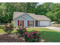 Charming single-story home boasts a well-manicured lawn, red shutters, and beautiful rose bushes in the front yard at 2889 Estuary Dr, Acworth, GA 30101